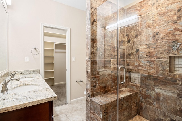 bathroom featuring double vanity, a sink, a spacious closet, and a shower stall
