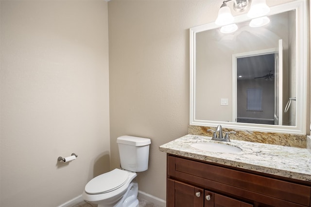 half bath featuring baseboards, toilet, and vanity