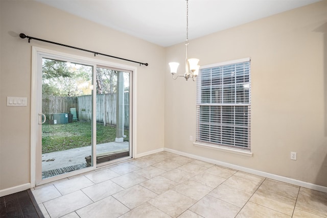 tiled empty room featuring an inviting chandelier and baseboards
