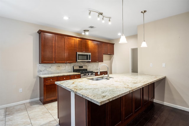 kitchen with light stone counters, a sink, tasteful backsplash, stainless steel appliances, and visible vents