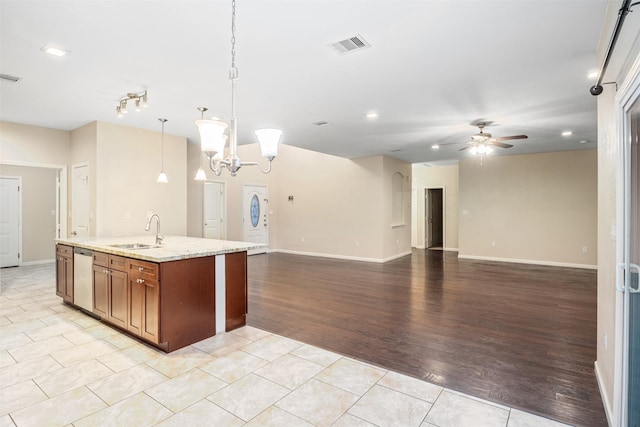 kitchen with ceiling fan with notable chandelier, hanging light fixtures, a sink, visible vents, and brown cabinets