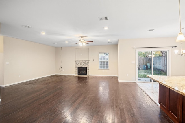 unfurnished living room with a fireplace with flush hearth, baseboards, dark wood-style floors, ceiling fan, and visible vents