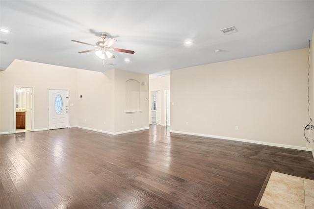 unfurnished living room with baseboards, dark wood-style flooring, visible vents, and a ceiling fan