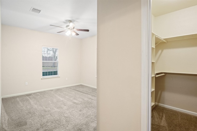 spacious closet featuring visible vents, carpet flooring, and a ceiling fan