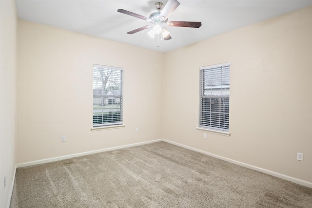 carpeted spare room with baseboards and a ceiling fan