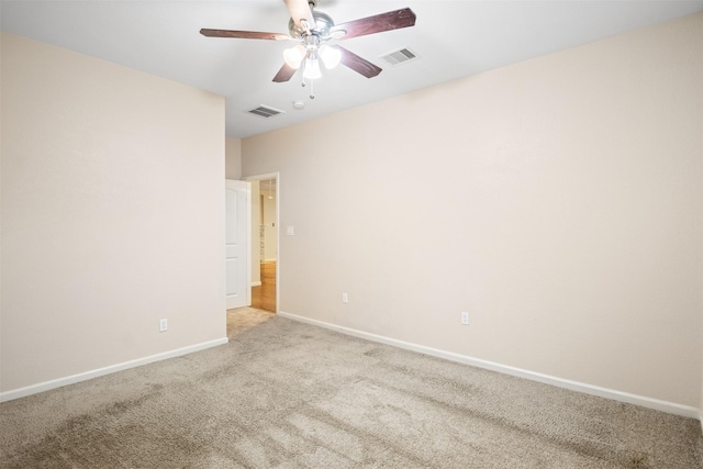 empty room featuring light colored carpet, visible vents, ceiling fan, and baseboards