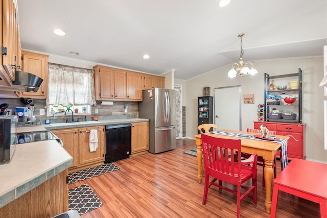 kitchen featuring freestanding refrigerator, black dishwasher, light wood-type flooring, tasteful backsplash, and a sink