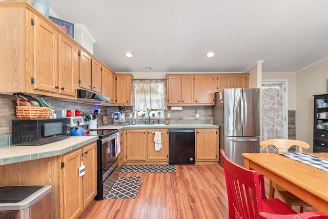 kitchen with crown molding, decorative backsplash, light wood-style floors, under cabinet range hood, and black appliances