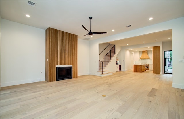unfurnished living room featuring stairs, visible vents, and light wood finished floors