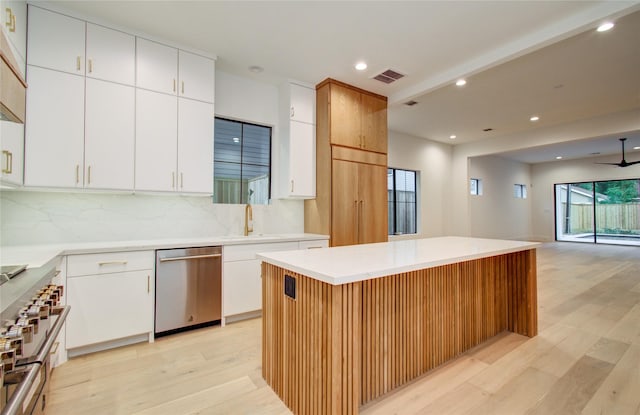 kitchen with a kitchen island, backsplash, open floor plan, stainless steel appliances, and light wood-style flooring