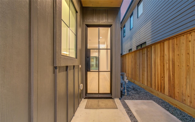 property entrance featuring board and batten siding and fence
