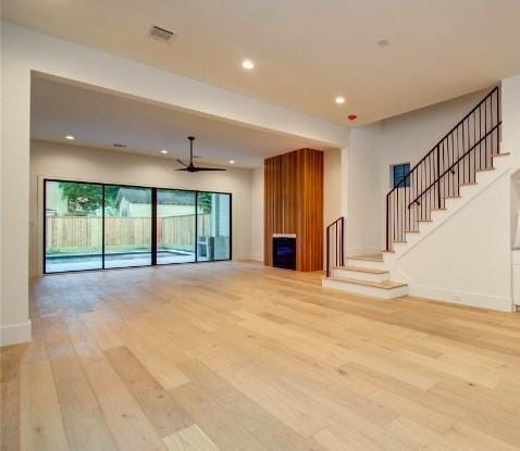 unfurnished living room with baseboards, light wood-style flooring, stairway, and a fireplace