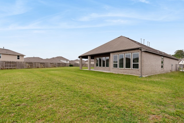 back of property featuring a fenced backyard, brick siding, and a yard