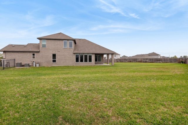 rear view of house featuring central air condition unit, roof with shingles, fence, and a yard