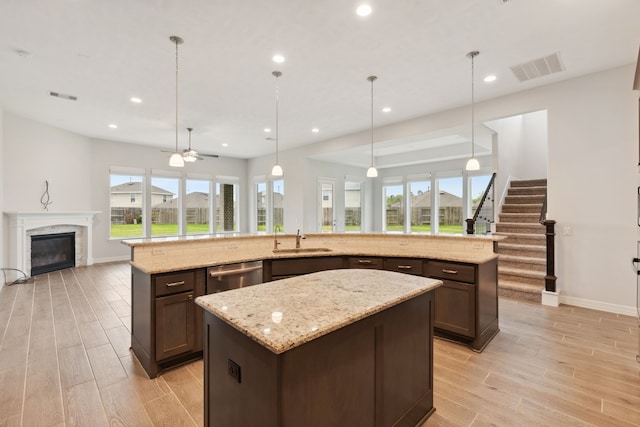 kitchen with recessed lighting, wood tiled floor, a sink, open floor plan, and a large island with sink