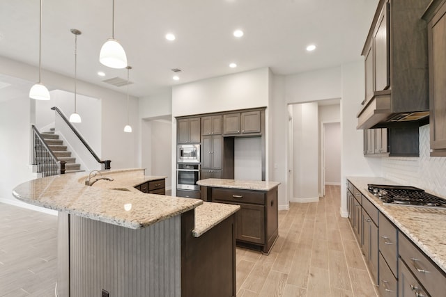 kitchen with a spacious island, a sink, tasteful backsplash, stainless steel appliances, and light wood-style floors
