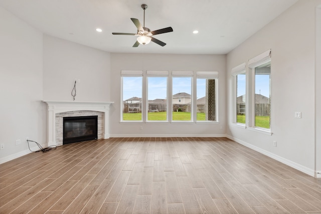 unfurnished living room featuring recessed lighting, baseboards, light wood finished floors, ceiling fan, and a glass covered fireplace