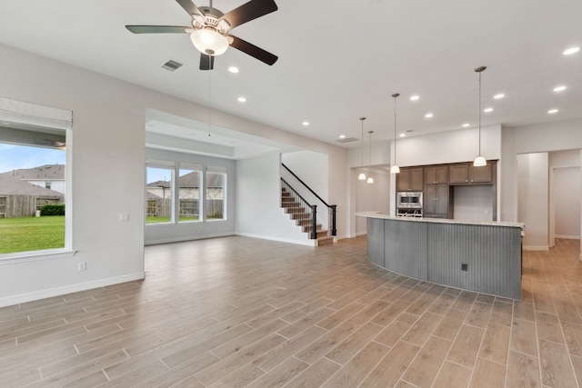 kitchen with light countertops, open floor plan, stainless steel appliances, visible vents, and light wood-style floors