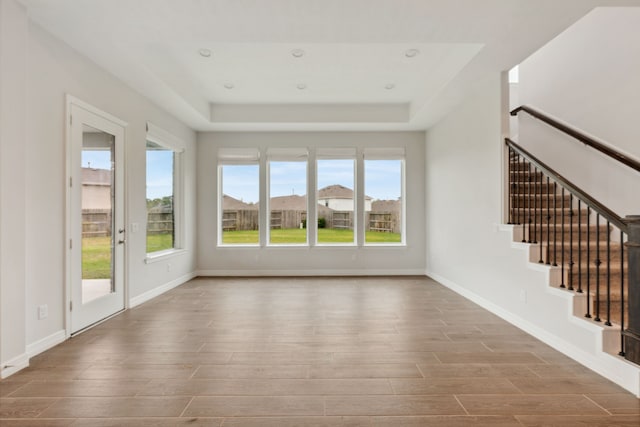 unfurnished living room featuring baseboards, wood finished floors, and stairway