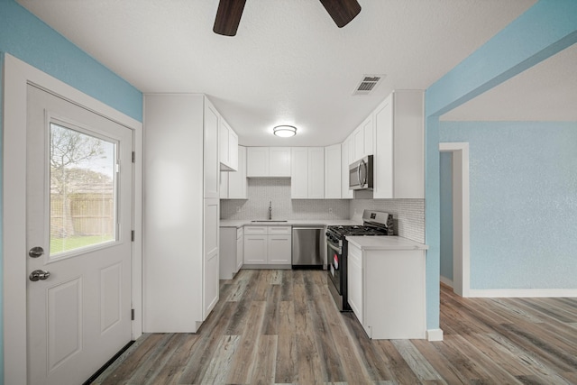 kitchen featuring ceiling fan, backsplash, visible vents, a sink, and stainless steel appliances