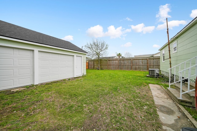 view of yard featuring central air condition unit, a garage, fence, and an outbuilding