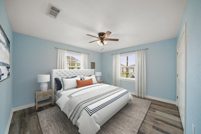 bedroom featuring visible vents, a ceiling fan, baseboards, and wood finished floors