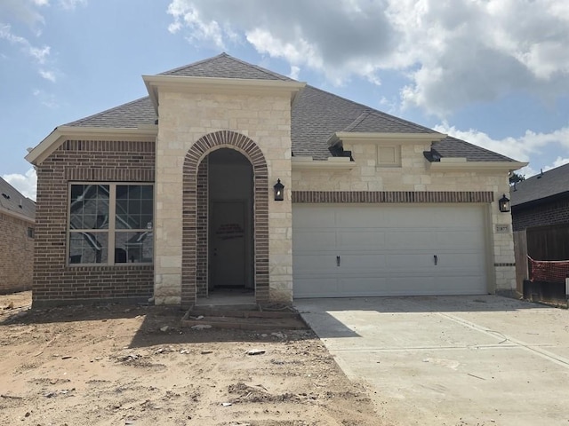 21877 Colorado Bend Ln, Porter, TX 77365 - french country inspired facade with roof with shingles, brick siding, stone siding, driveway, and an attached garage