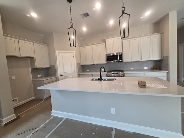 21877 Colorado Bend Ln, Porter, TX 77365 - kitchen featuring appliances with stainless steel finishes, decorative backsplash, a large island with sink, white cabinetry, and light countertops