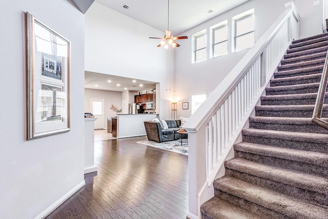 1100 Lasso Ct, Alvin, TX 77511 - staircase featuring visible vents, a towering ceiling, baseboards, a ceiling fan, and wood-type flooring