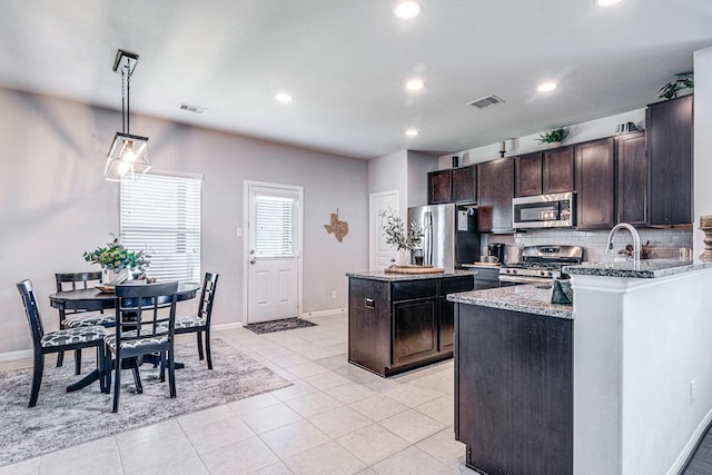 1100 Lasso Ct, Alvin, TX 77511 - kitchen with backsplash, visible vents, light stone countertops, a center island, and appliances with stainless steel finishes