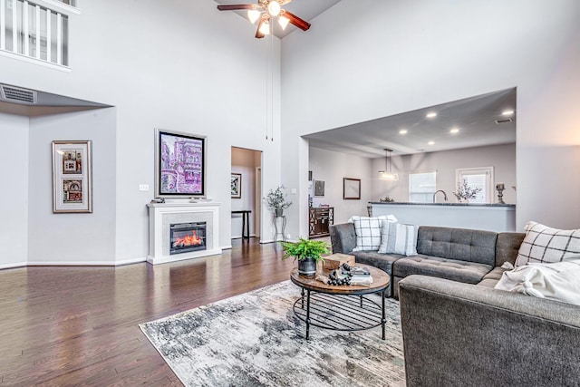 1100 Lasso Ct, Alvin, TX 77511 - living room featuring a towering ceiling, wood finished floors, a glass covered fireplace, and ceiling fan