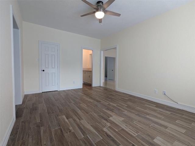unfurnished bedroom featuring baseboards, ensuite bathroom, a ceiling fan, and dark wood finished floors
