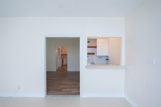 kitchen with backsplash, light countertops, baseboards, and wood finished floors