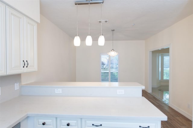 kitchen featuring white cabinetry, light countertops, visible vents, a peninsula, and wood finished floors