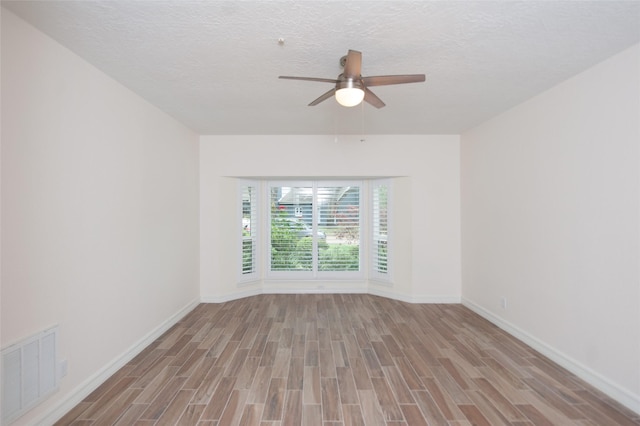 unfurnished room with baseboards, visible vents, wood finished floors, and ceiling fan