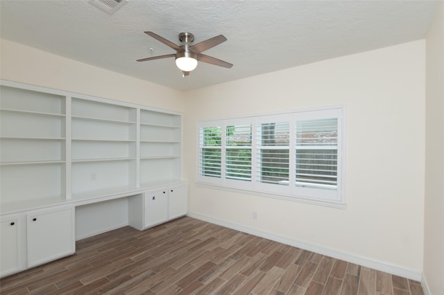 spare room featuring dark wood-style flooring, baseboards, a textured ceiling, visible vents, and ceiling fan