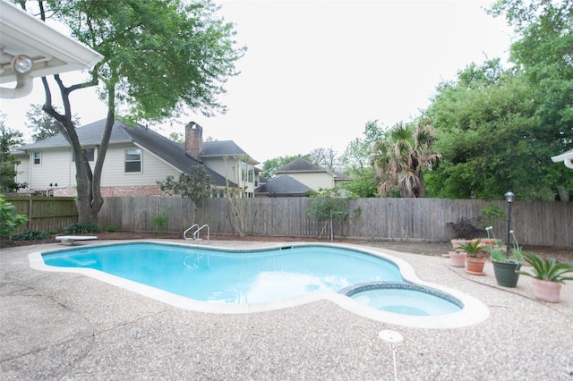 view of swimming pool featuring a fenced backyard, a pool with connected hot tub, and a patio
