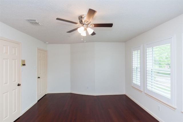 unfurnished room with baseboards, dark wood finished floors, a textured ceiling, ceiling fan, and visible vents
