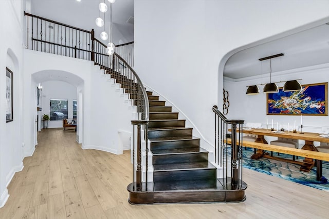 stairway with baseboards, a high ceiling, wood finished floors, and arched walkways