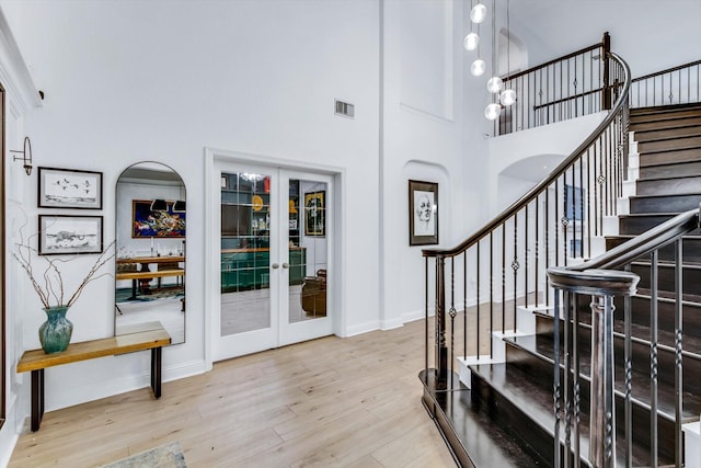 foyer entrance featuring visible vents, baseboards, stairs, wood finished floors, and french doors