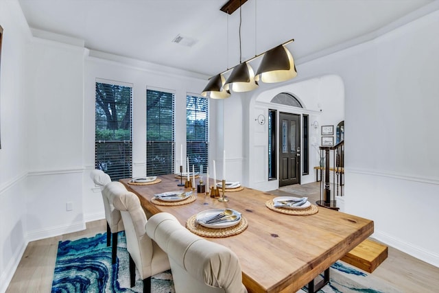 dining space featuring visible vents, arched walkways, baseboards, and wood finished floors