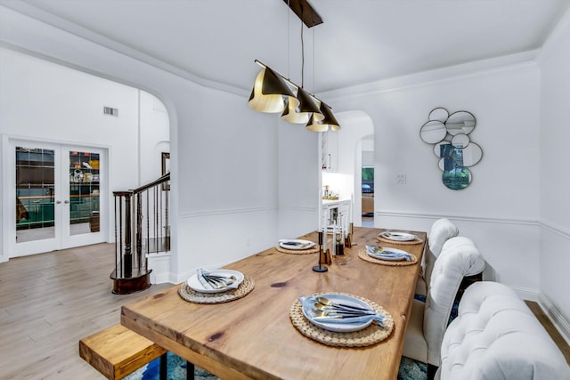 dining space featuring visible vents, stairs, ornamental molding, wood finished floors, and arched walkways
