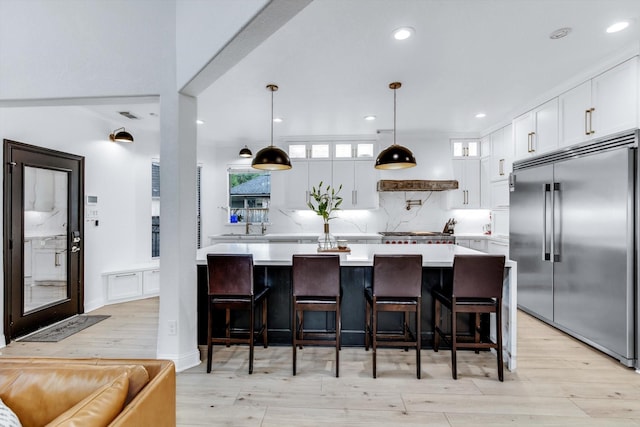 kitchen with stainless steel built in fridge, glass insert cabinets, light countertops, and tasteful backsplash