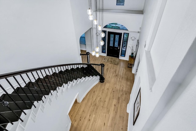 entryway with stairs, wood finished floors, and a towering ceiling
