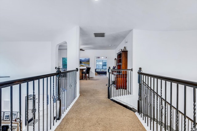 hall featuring light colored carpet, visible vents, and arched walkways