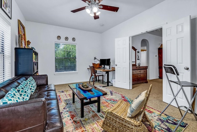 living area with lofted ceiling, carpet flooring, baseboards, arched walkways, and a ceiling fan