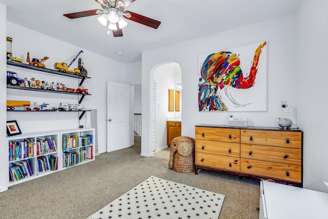 carpeted bedroom with arched walkways, ceiling fan, and ensuite bathroom