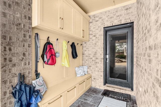 mudroom featuring brick wall