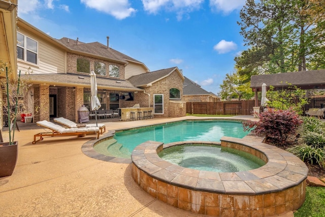 view of pool featuring a patio, fence, a pool with connected hot tub, and outdoor dry bar