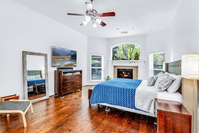 bedroom with a fireplace, visible vents, ceiling fan, and hardwood / wood-style flooring